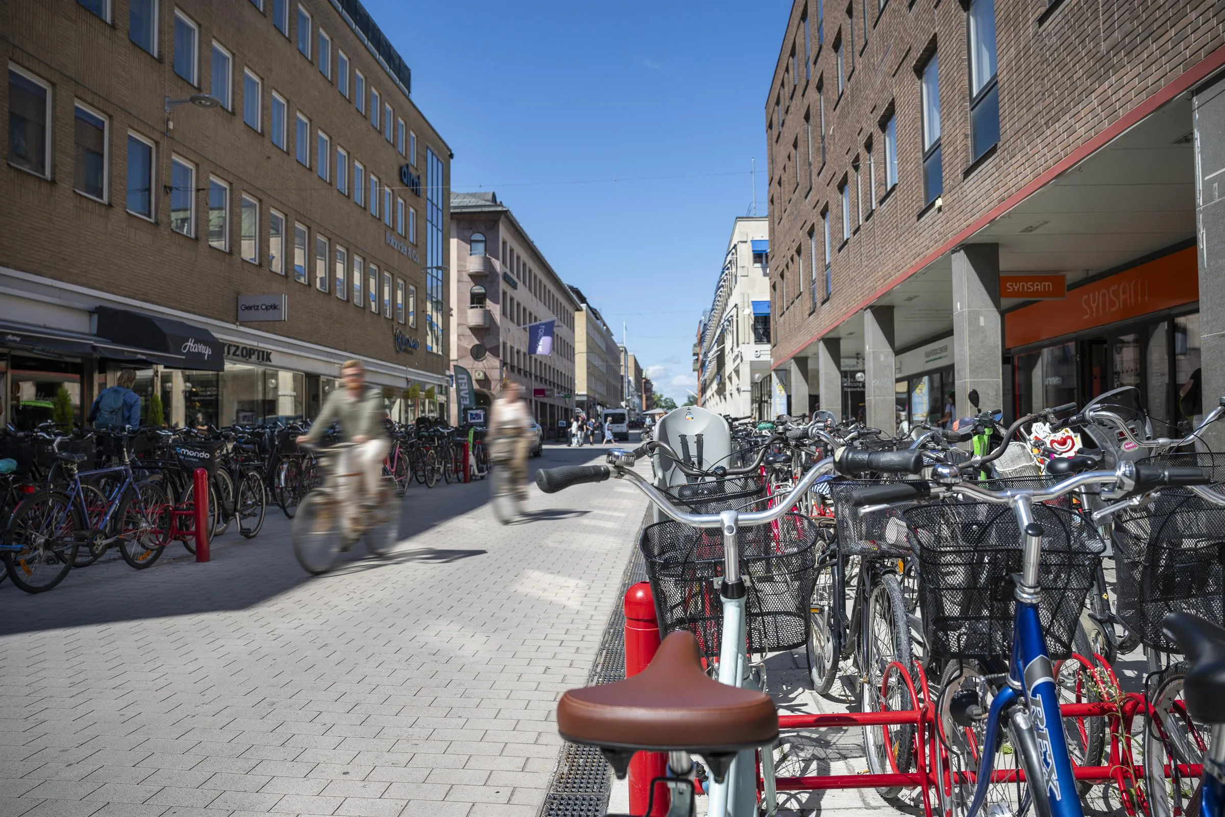3. En gata med cyklar parkerade längs sidan och människor som går och cyklar.