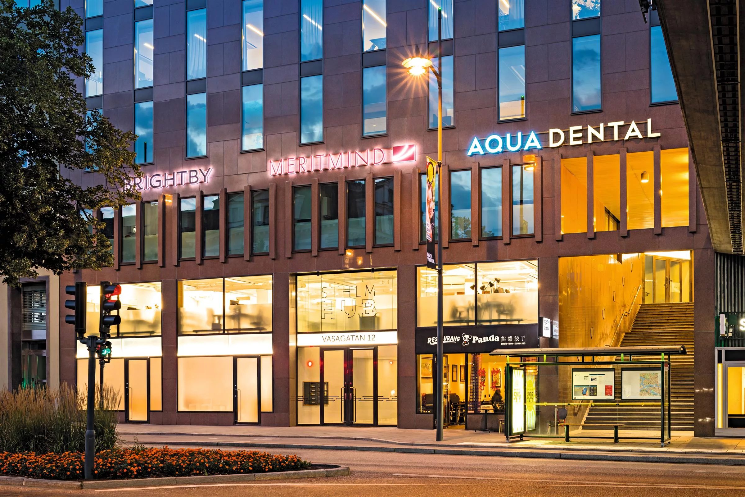 Byggnadsfasad med skyltar som lyser, inklusive "Aqua Dental".