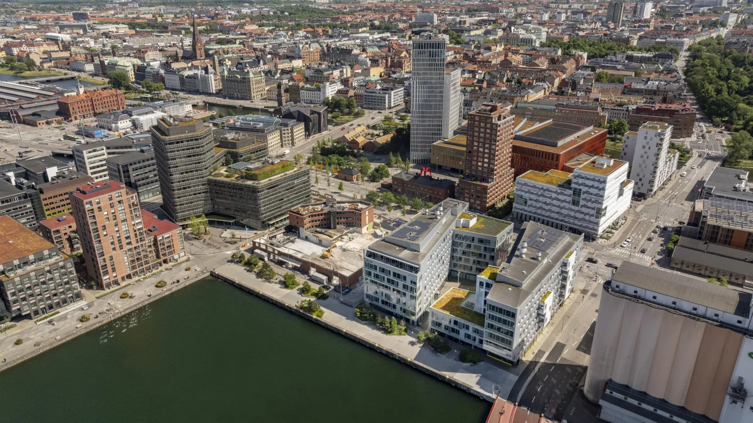 Flygvy över en stad med moderna byggnader, en kanal och en blandning av arkitektur.