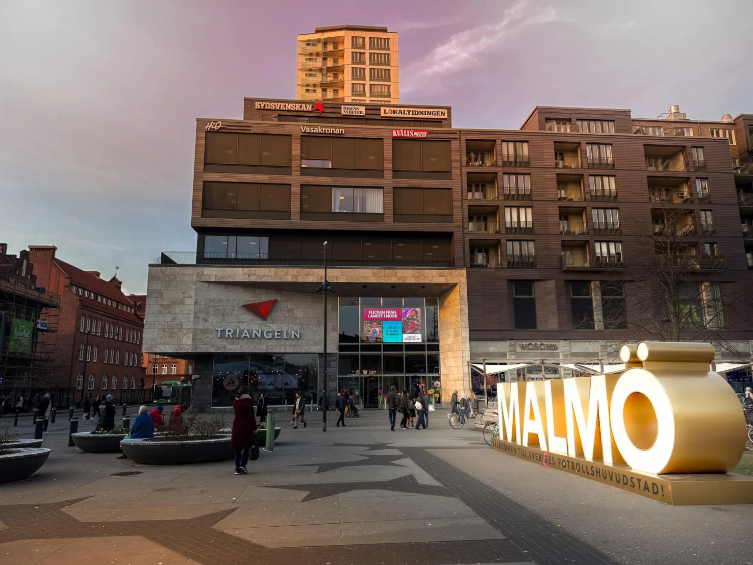 Ett torg i Malmö med byggnader i bakgrunden och stora ljusskyltar som stavar "MALMÖ".