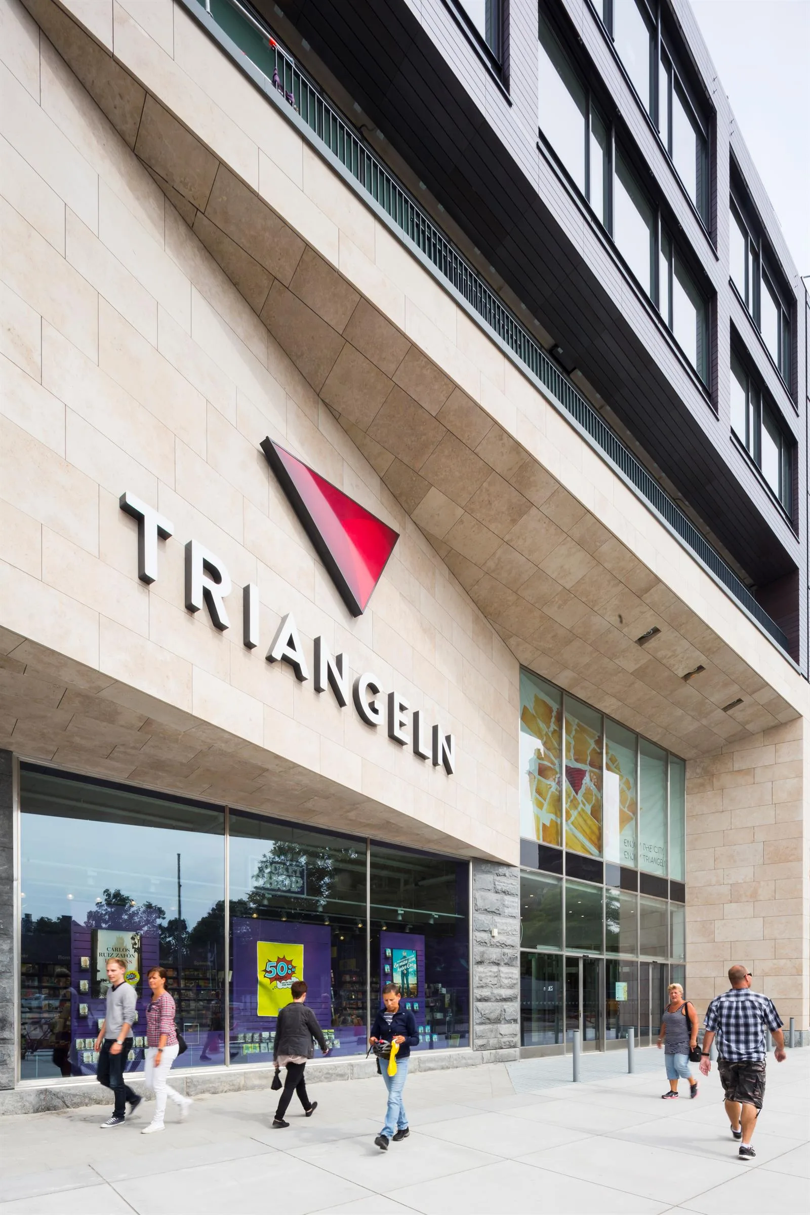Närbild på entrén till Triangeln med en röd triangelformad logotyp och texten "Triangeln" på fasaden.
