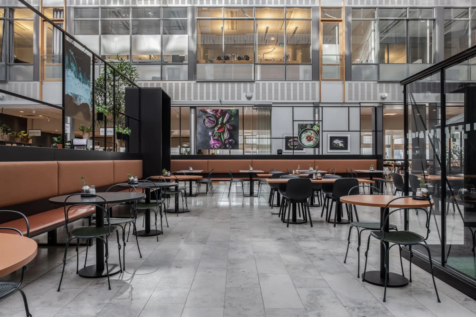 2. En rymlig restaurang med moderna möbler, stora glasväggar och konstverk på väggarna.