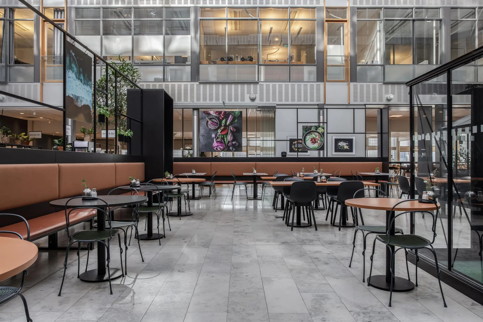 2. En rymlig restaurang med moderna möbler, stora glasväggar och konstverk på väggarna.