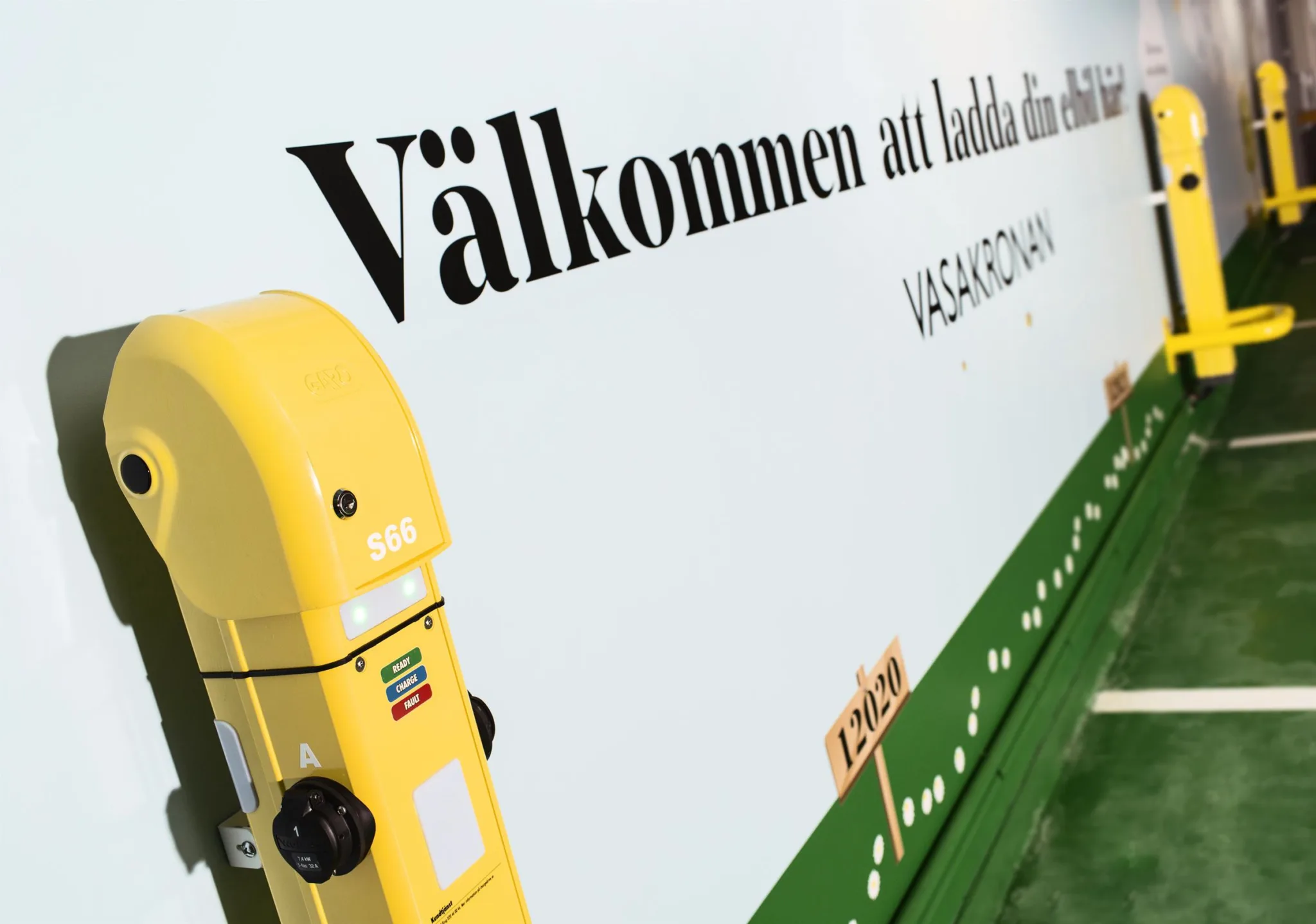 3. En gul laddningsstation och texten "Välkommen att ladda din bil" på en vit bakgrund.