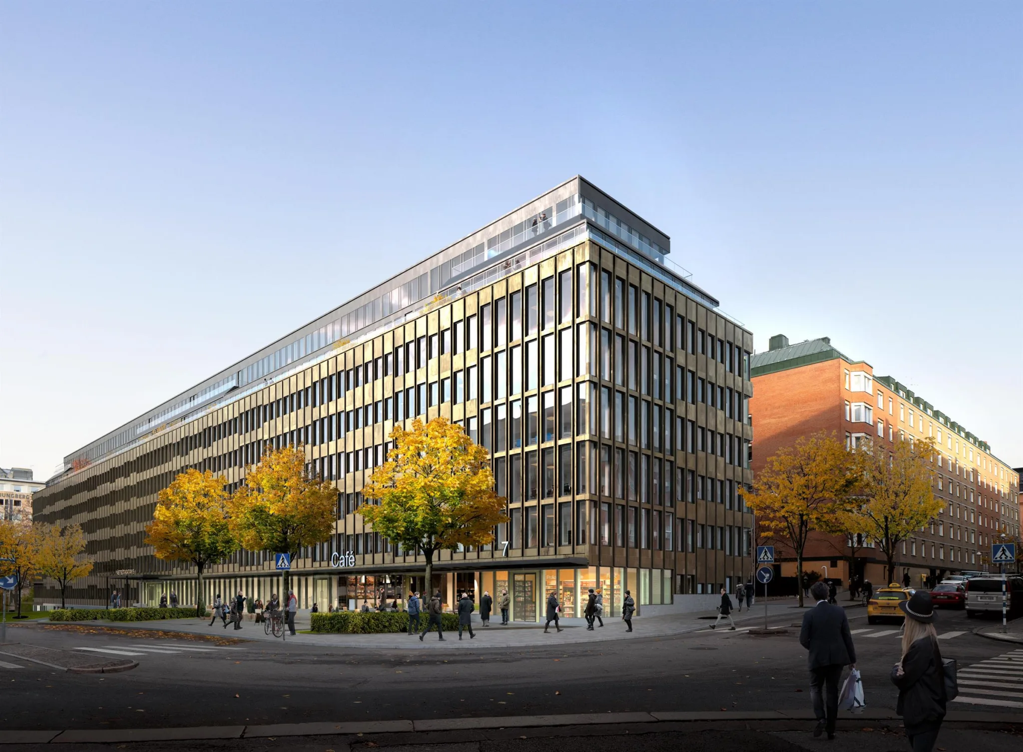 En modern byggnad med glasfasad och höstfärgade träd vid trottoaren.