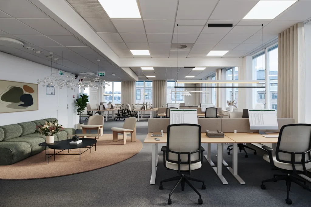 Ett modernt kontor med öppet landskap, skrivbord och stolar samt stora fönster som släpper in naturligt ljus.