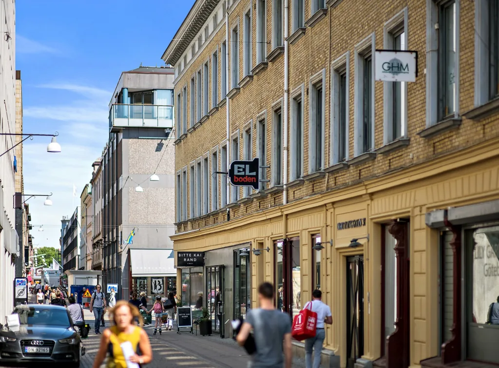 4. Gata med en beige byggnad, butiker och människor som promenerar.