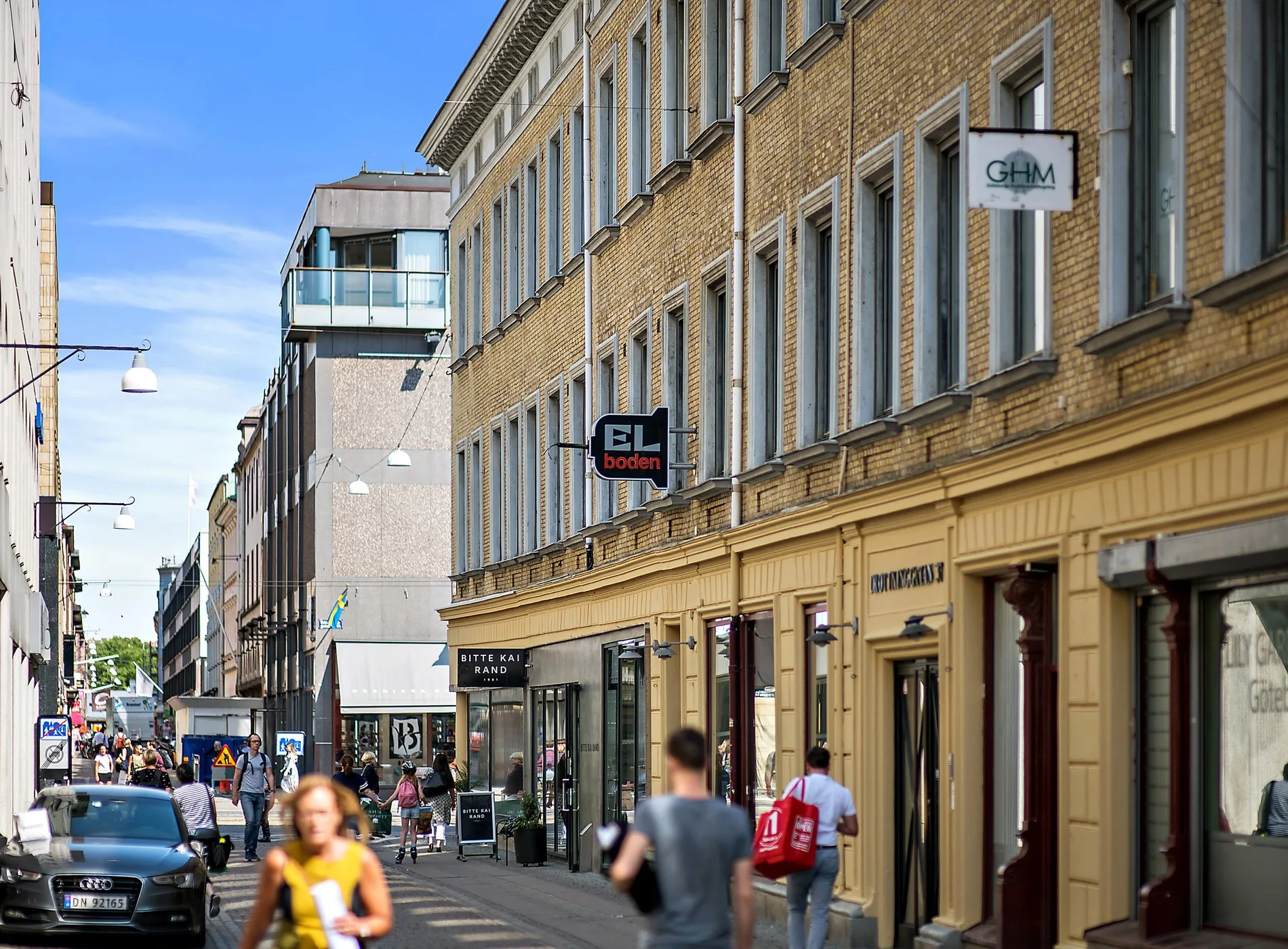 4. Gata med en beige byggnad, butiker och människor som promenerar.
