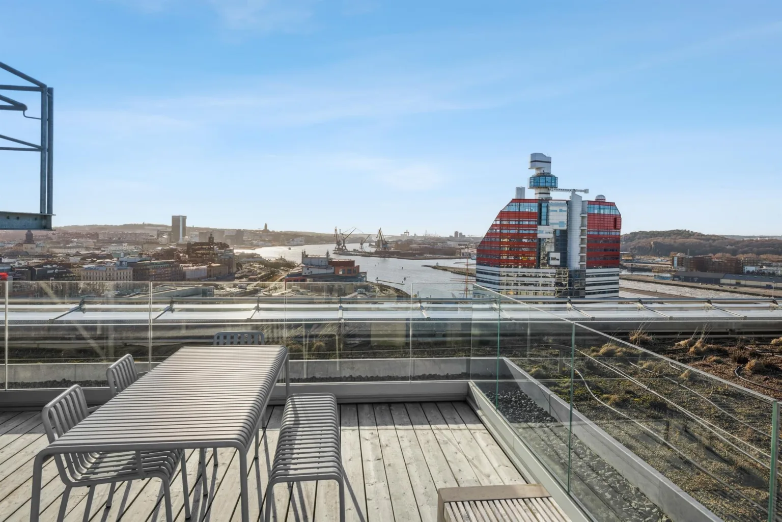 En takterrass med utsikt över en flod och en rödvit byggnad.