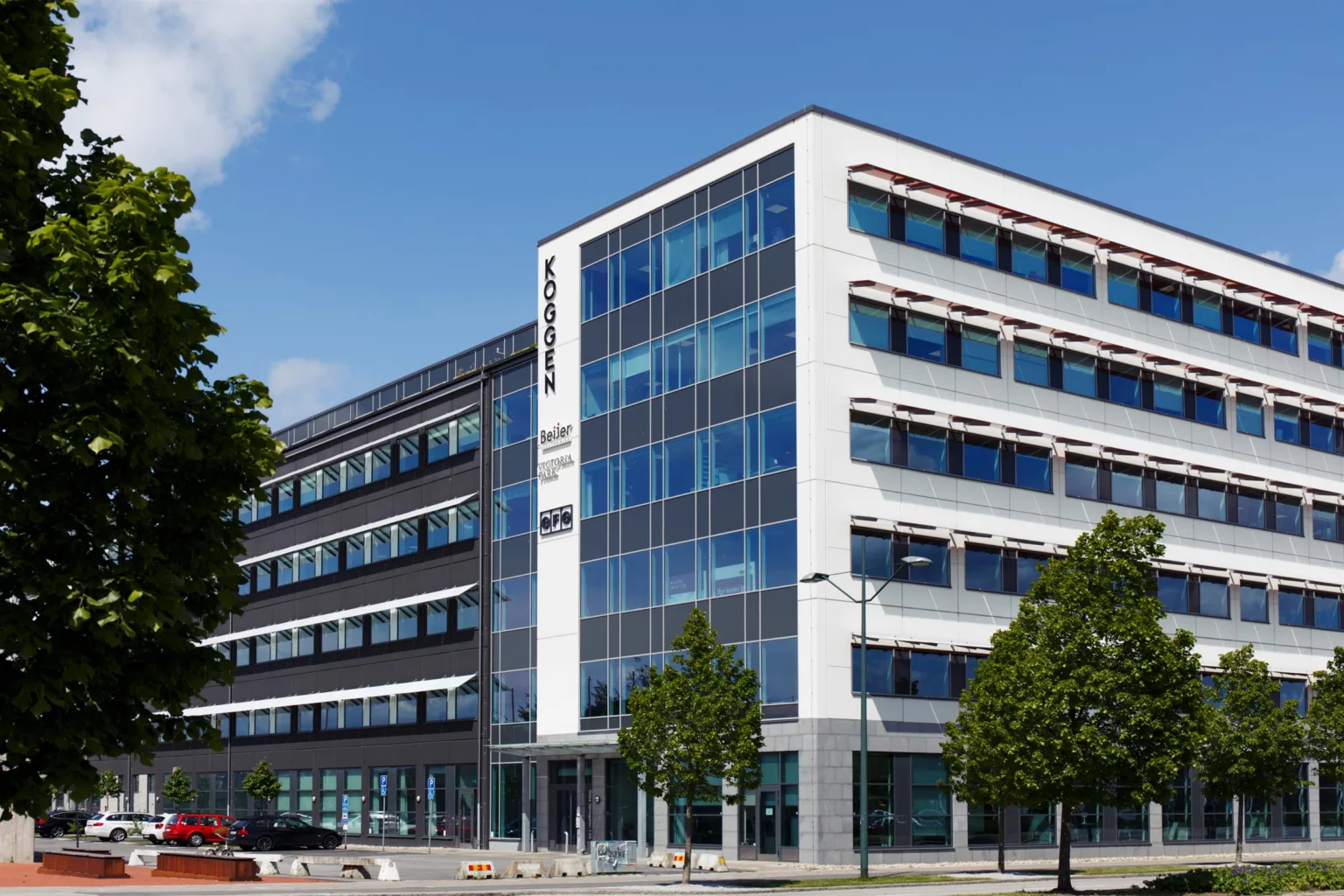 En modern kontorsbyggnad med glasfasad och en skylt med texten "Innovatum", omgiven av träd och trottoarer.