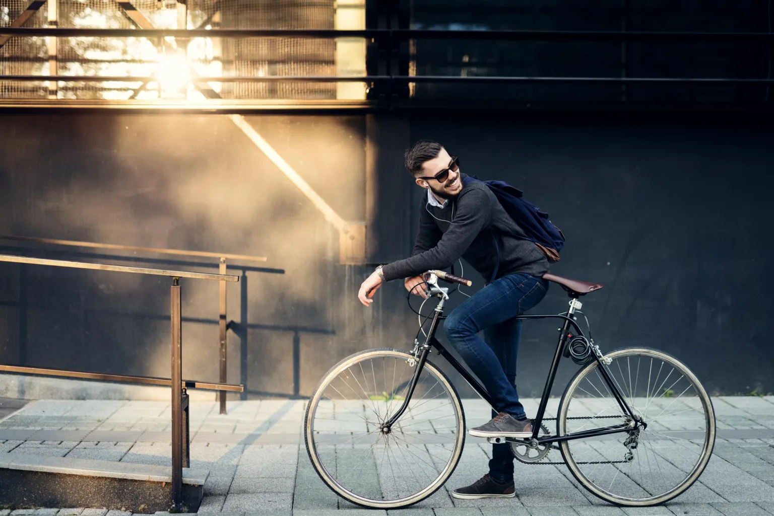 En man cyklar på en stadsgata med solstrålar i bakgrunden.