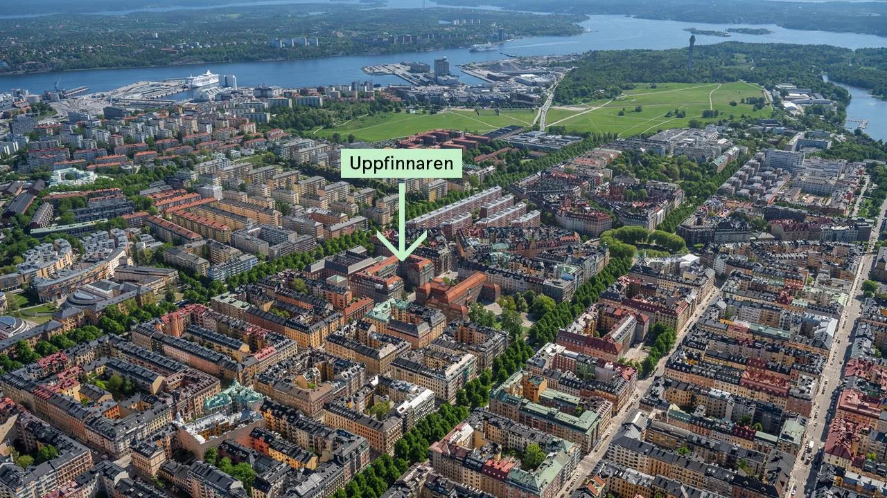 Flygbild över en stad med en grön skylt som pekar mot en byggnad markerad som "Uppfinnaren".