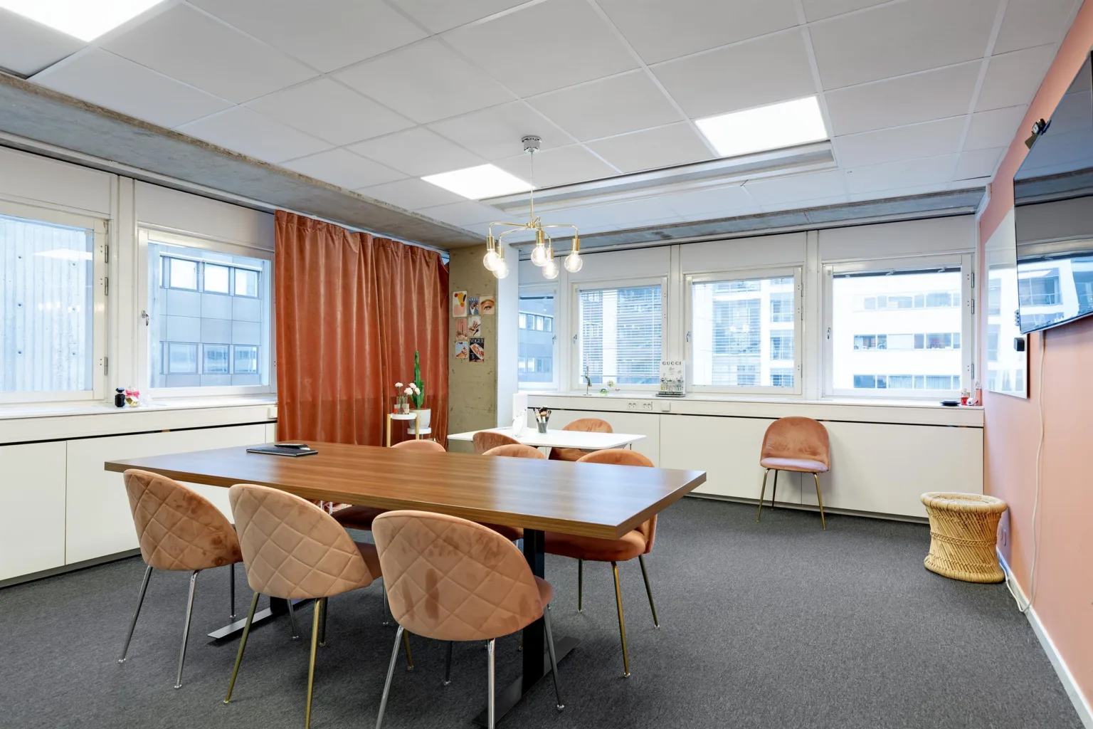 5. Ett mötesrum med bord och stolar, röda gardiner och stora fönster som släpper in naturligt ljus.
