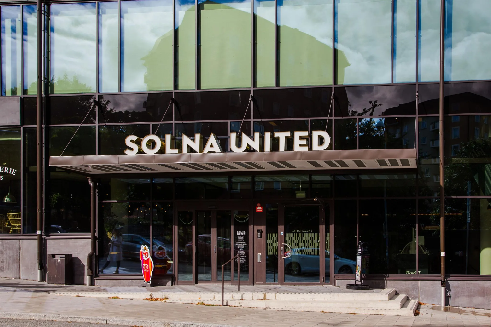 Entré till byggnaden "Solna United" med glasfasad och stora bokstäver.