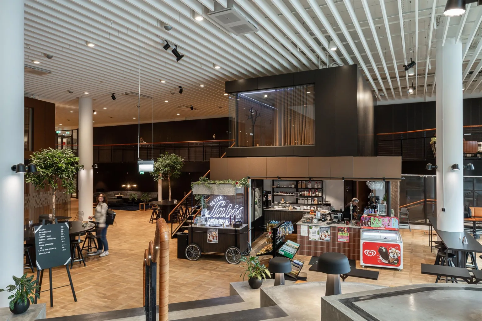 Ett café- eller receptionområde med en butik, sittplatser och en våning ovanför.