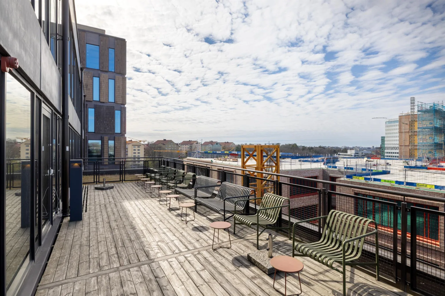 3. En takterrass med trämöbler och utsikt över en stad under en himmel med tunna moln.