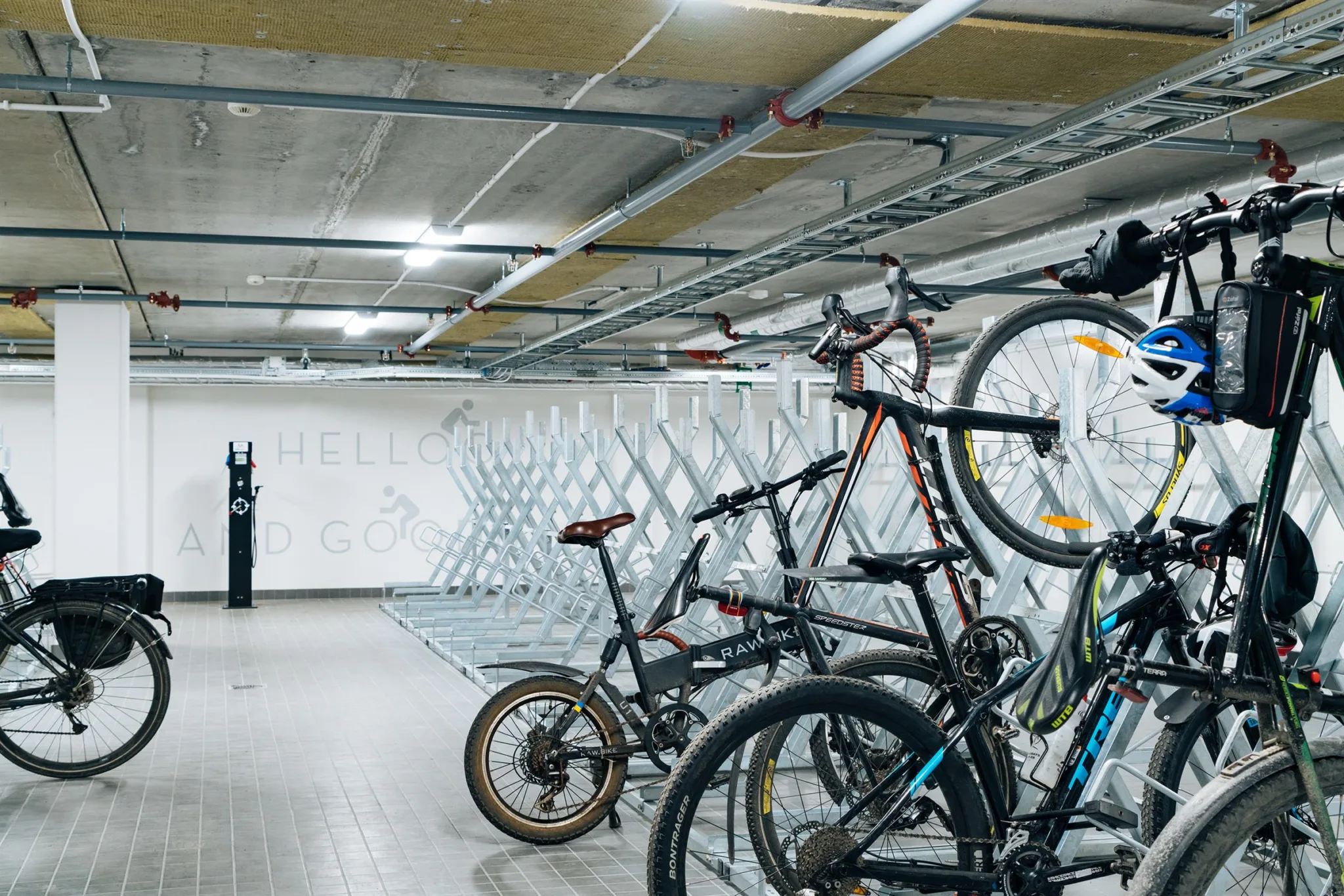 3. Ett cykelgarage med flera cyklar parkerade och upphängda på väggställningar i en väl upplyst källarlokal.