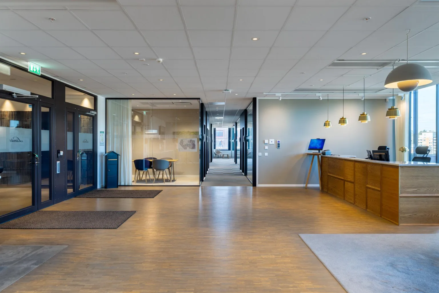 En rymlig kontorsentré med reception, sittplatser och korridor i bakgrunden.