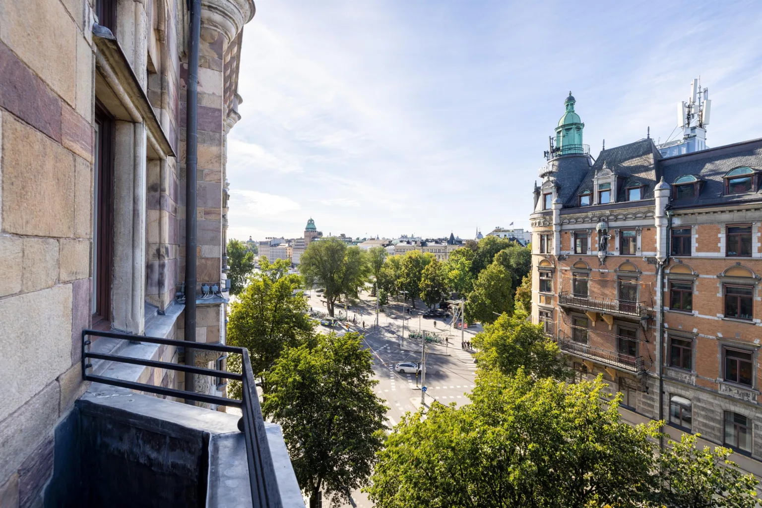 5. Utsikt från en balkong över ett torg med träd samt stora historiska byggnader.