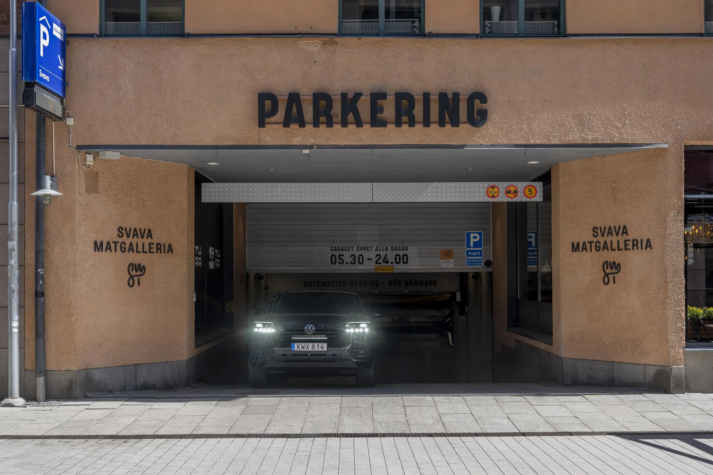En bil kör ut från en parkeringsgarage med texten "PARKERING" ovanför ingången.