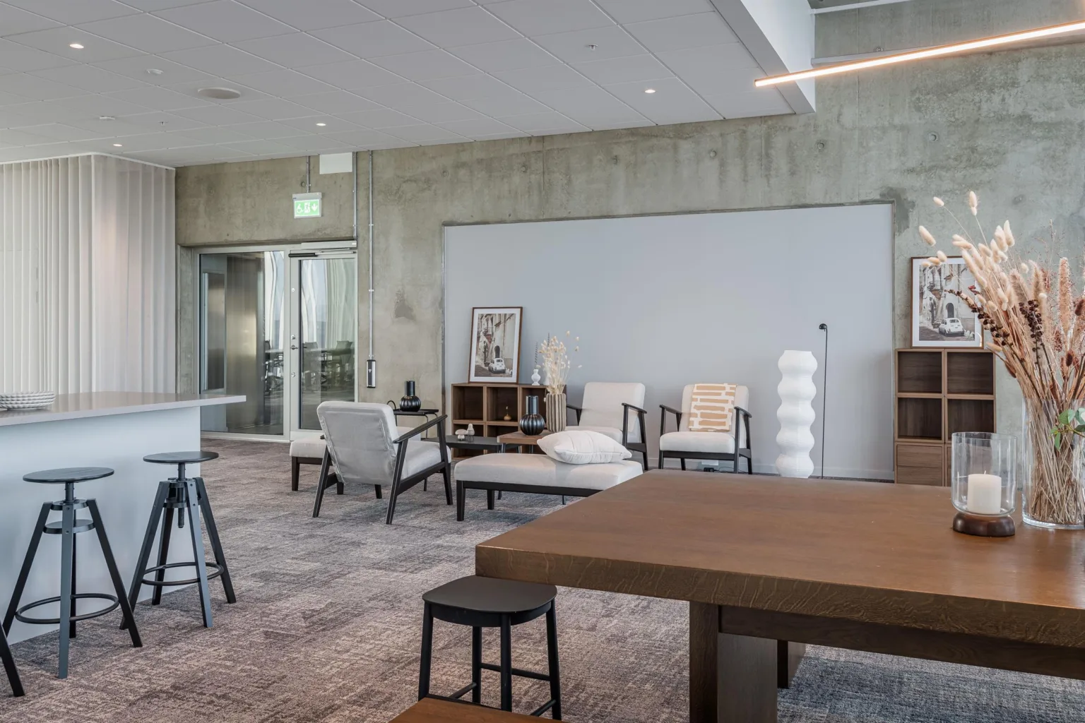 2. Ett stilrent loungeområde med soffor, fåtöljer och en tavla vid en vit vägg.
