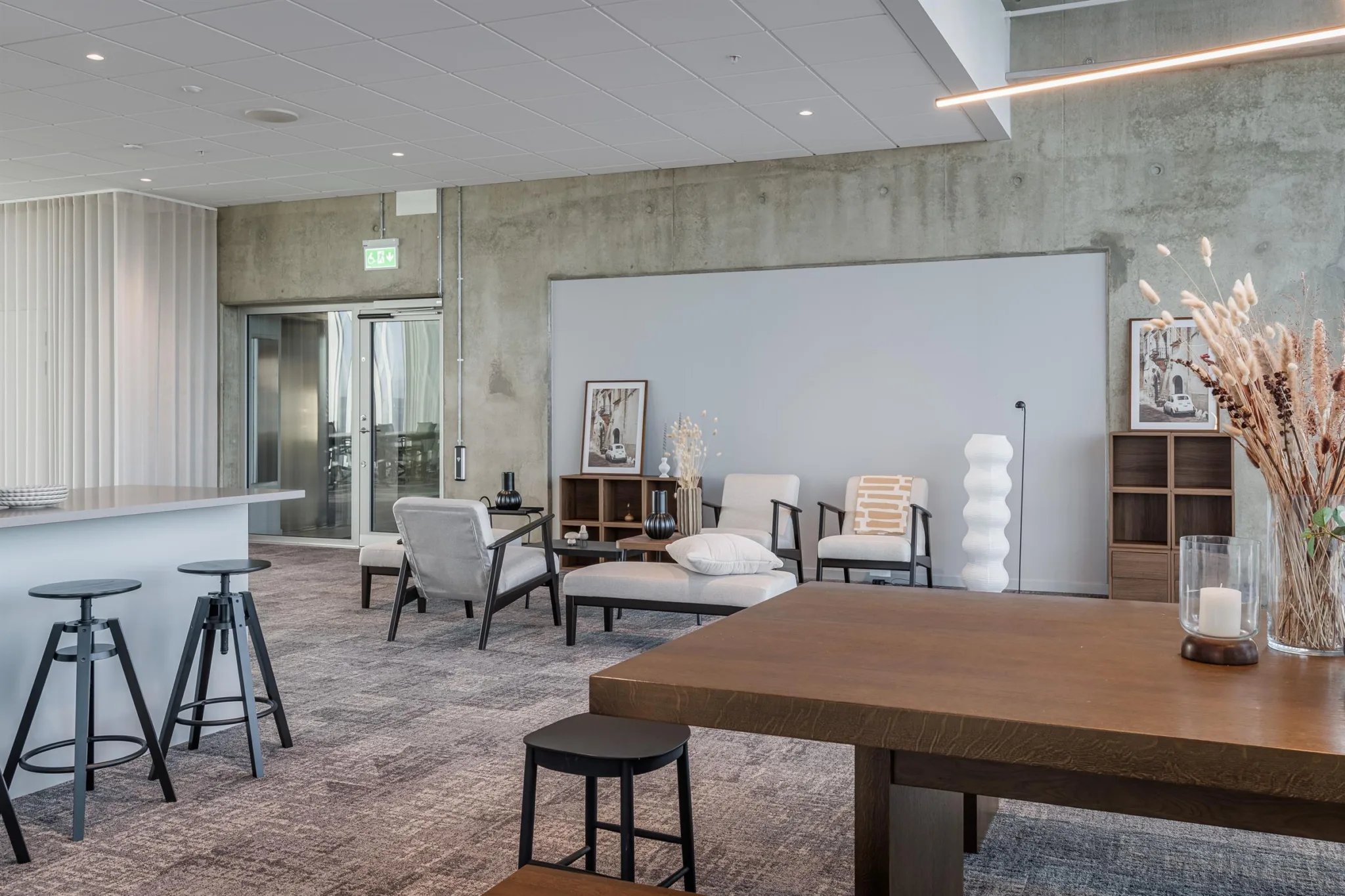 2. Ett stilrent loungeområde med soffor, fåtöljer och en tavla vid en vit vägg.