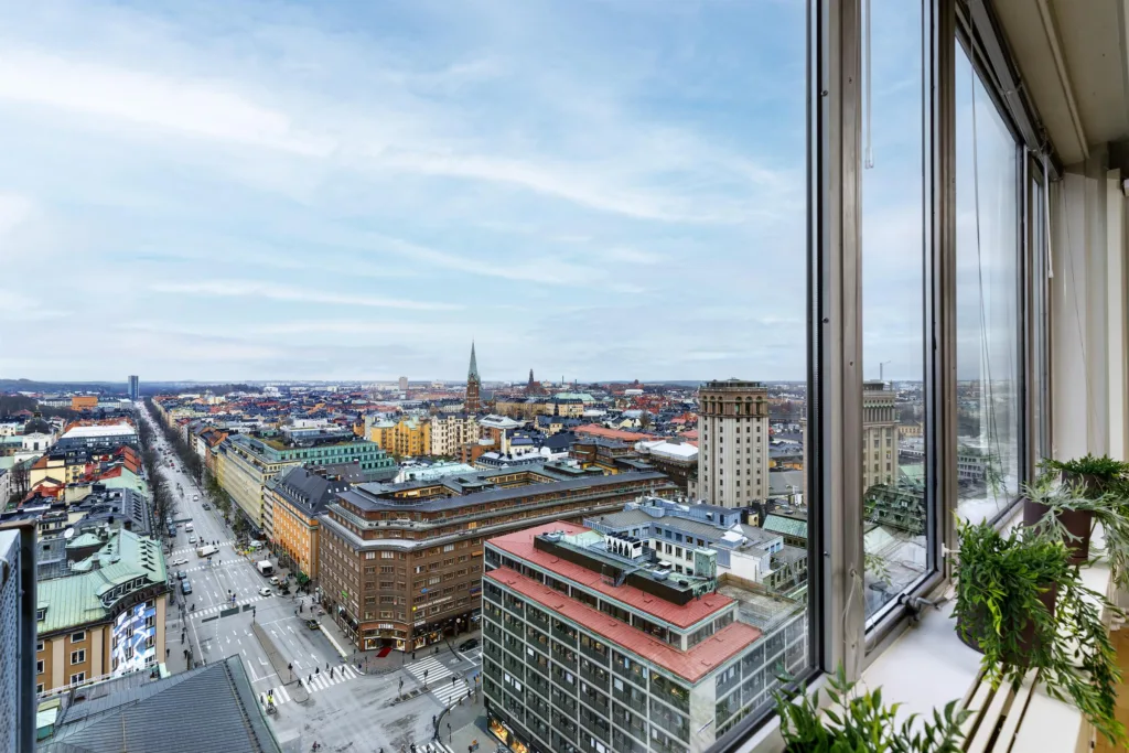 Stadsutsikt från hög höjd med byggnader, kyrktorn och klar himmel.