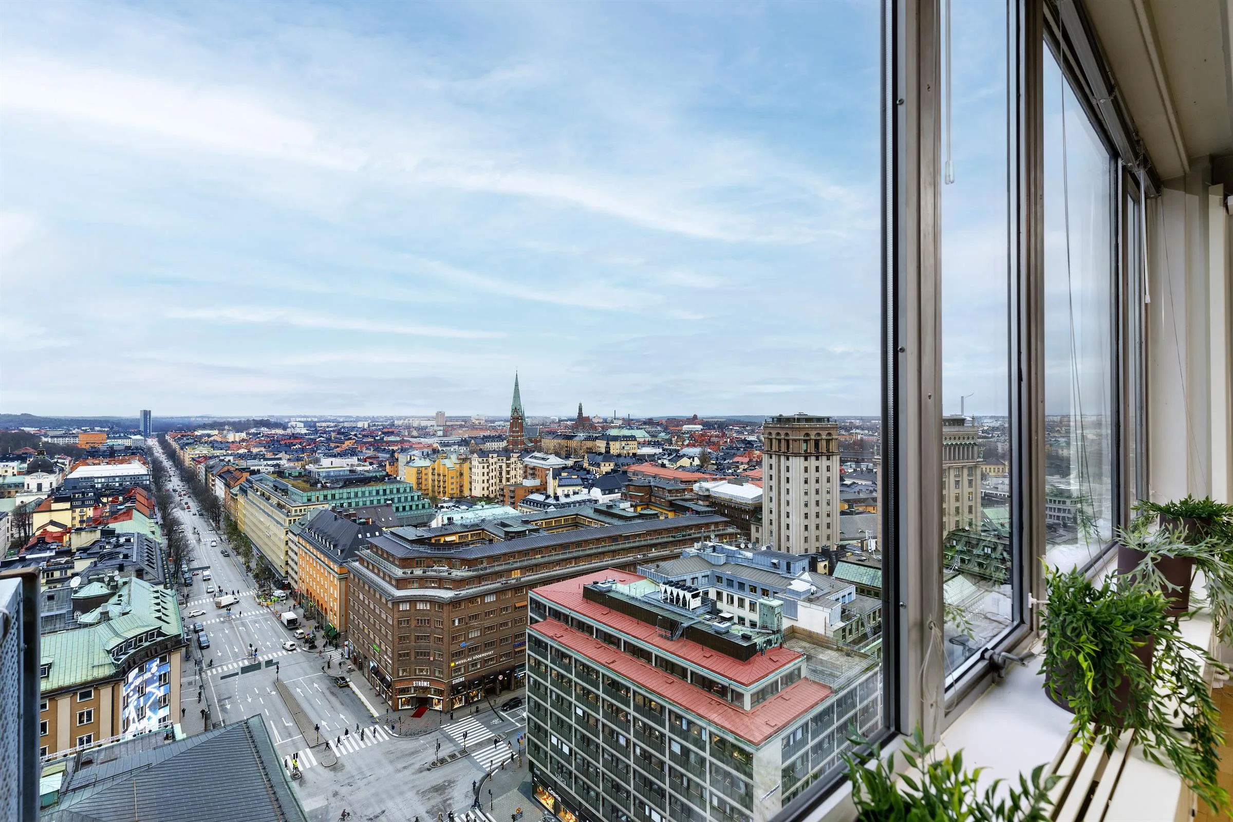 Stadsutsikt från hög höjd med byggnader, kyrktorn och klar himmel.