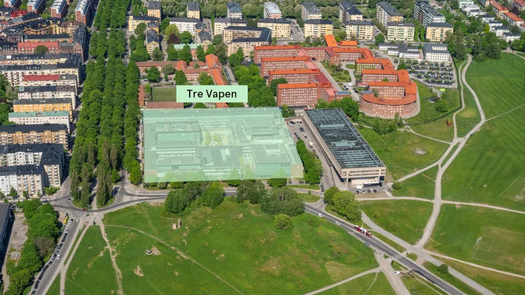 Flygfoto över ett område med byggnader, med texten "Tre Vapen" markerad på en grön yta.