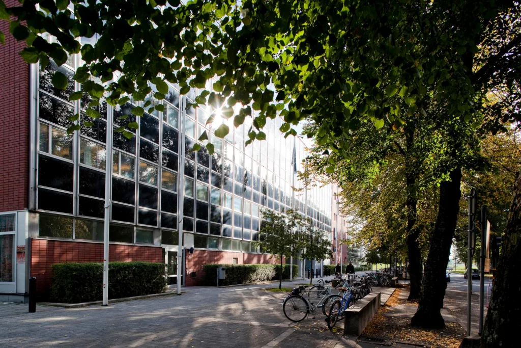 2. En modern glasbyggnad med träd och cyklar längs en gångväg i förgrunden.