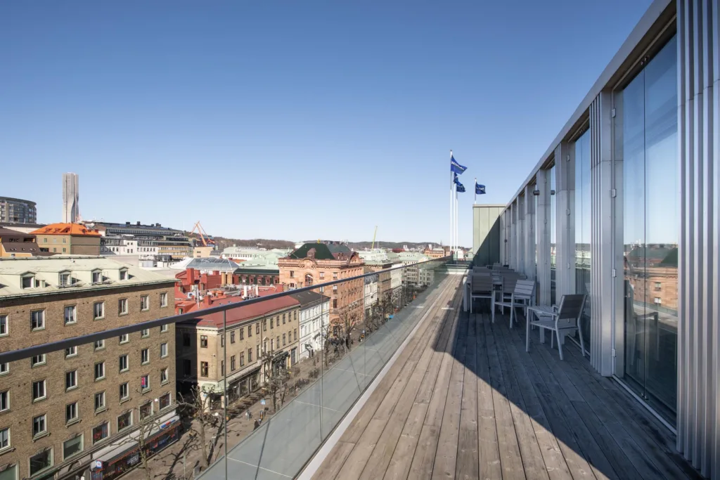 3. En takterrass med trätrall, utsikt över färgglada byggnader och en blå himmel.
