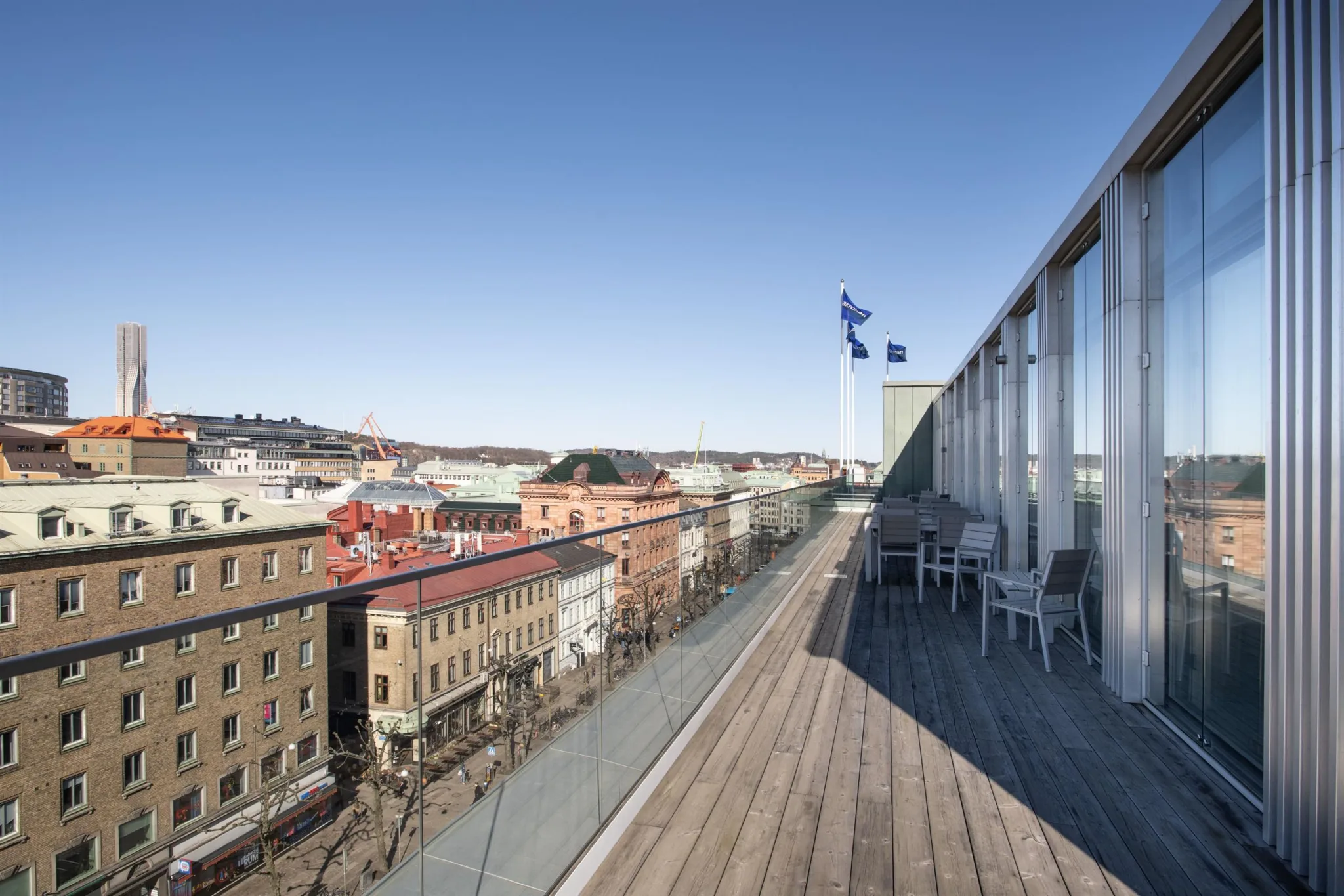 3. En takterrass med trätrall, utsikt över färgglada byggnader och en blå himmel.