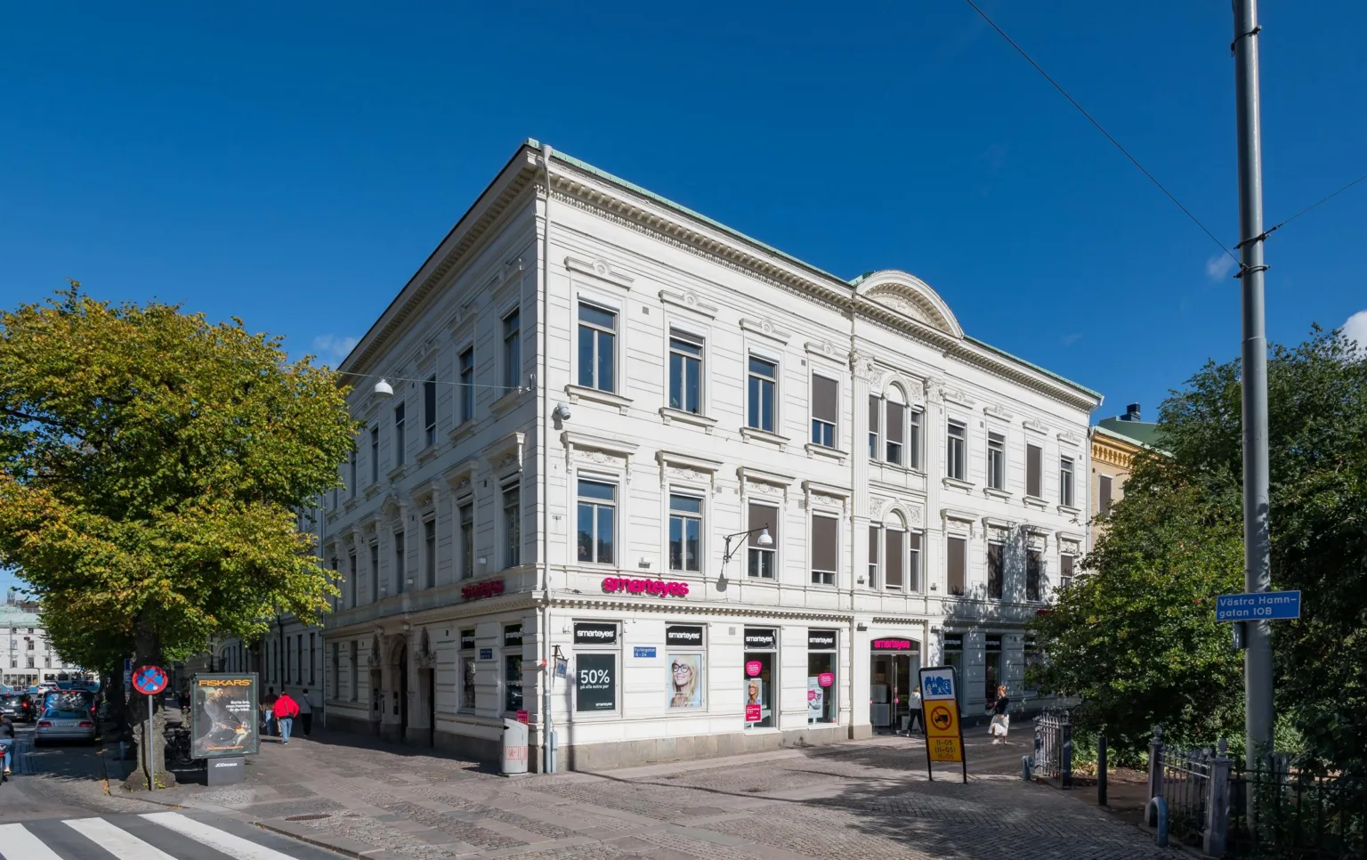 4. En vit byggnad med flera fönster och butiker på bottenvåningen, fotograferad under en klarblå himmel.