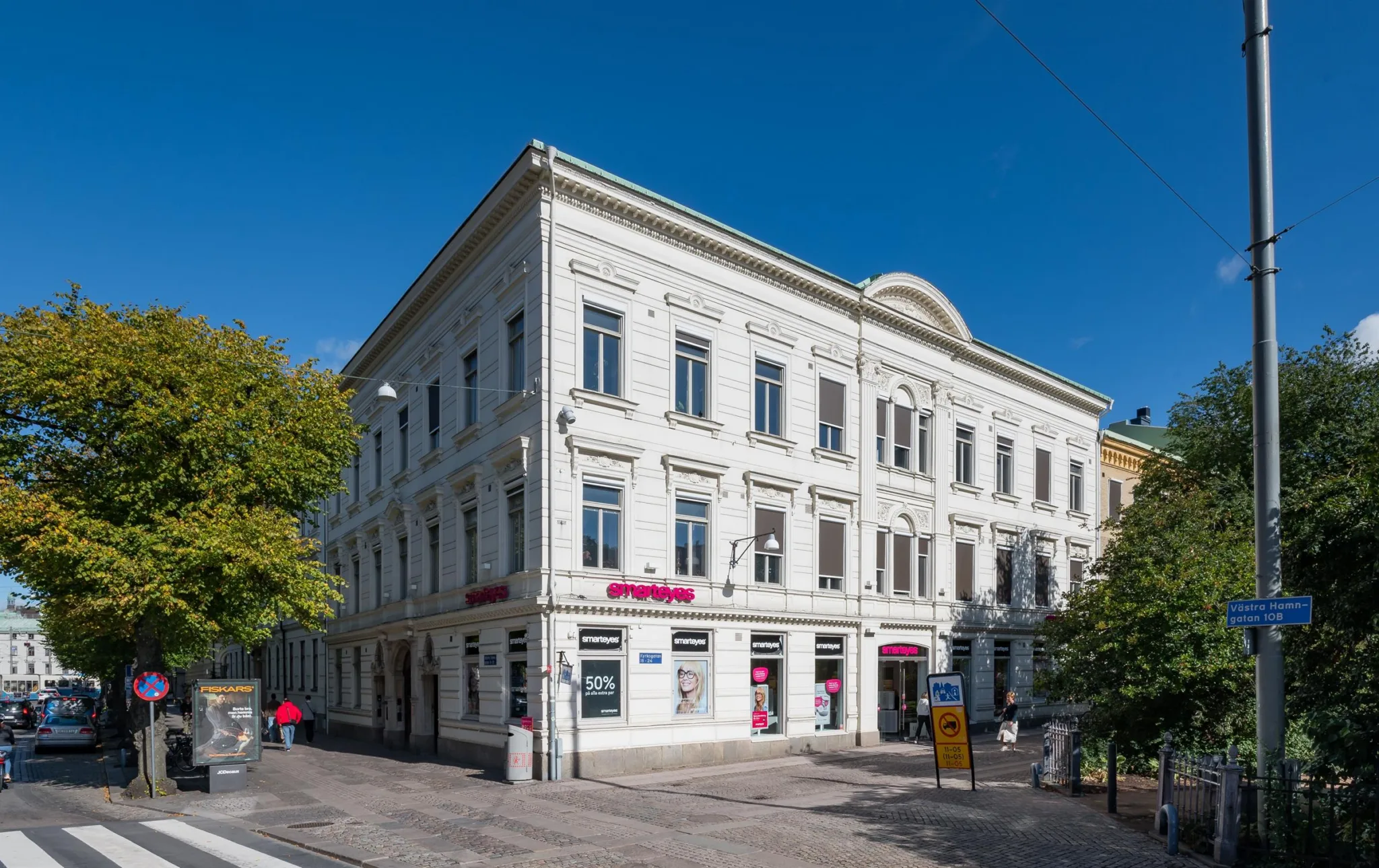 4. En vit byggnad med flera fönster och butiker på bottenvåningen, fotograferad under en klarblå himmel.