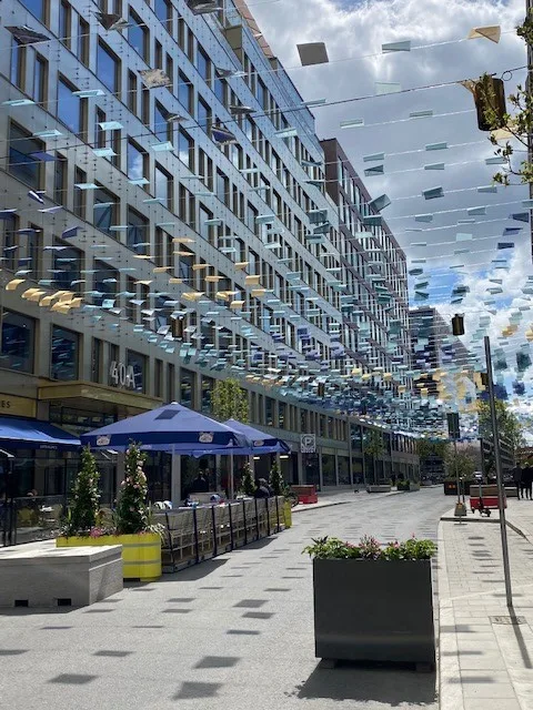 5. Gata med moderna byggnader, uteserveringar med parasoller och dekorationer hängande över gatan.