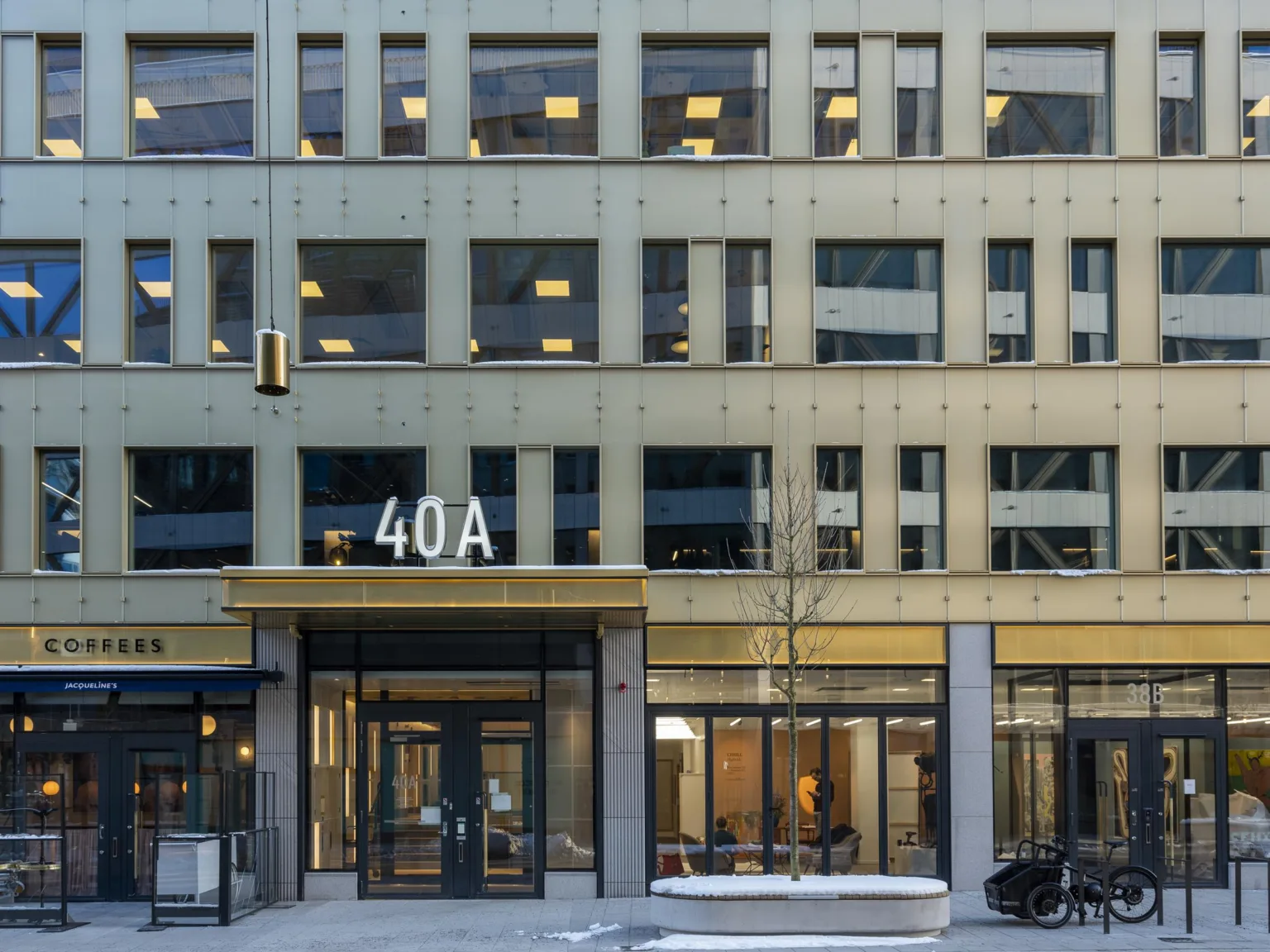 En byggnad med adressen 40A tydligt markerad ovanför ingången, med glasfasad och fönster som visar kontor och interiör.
