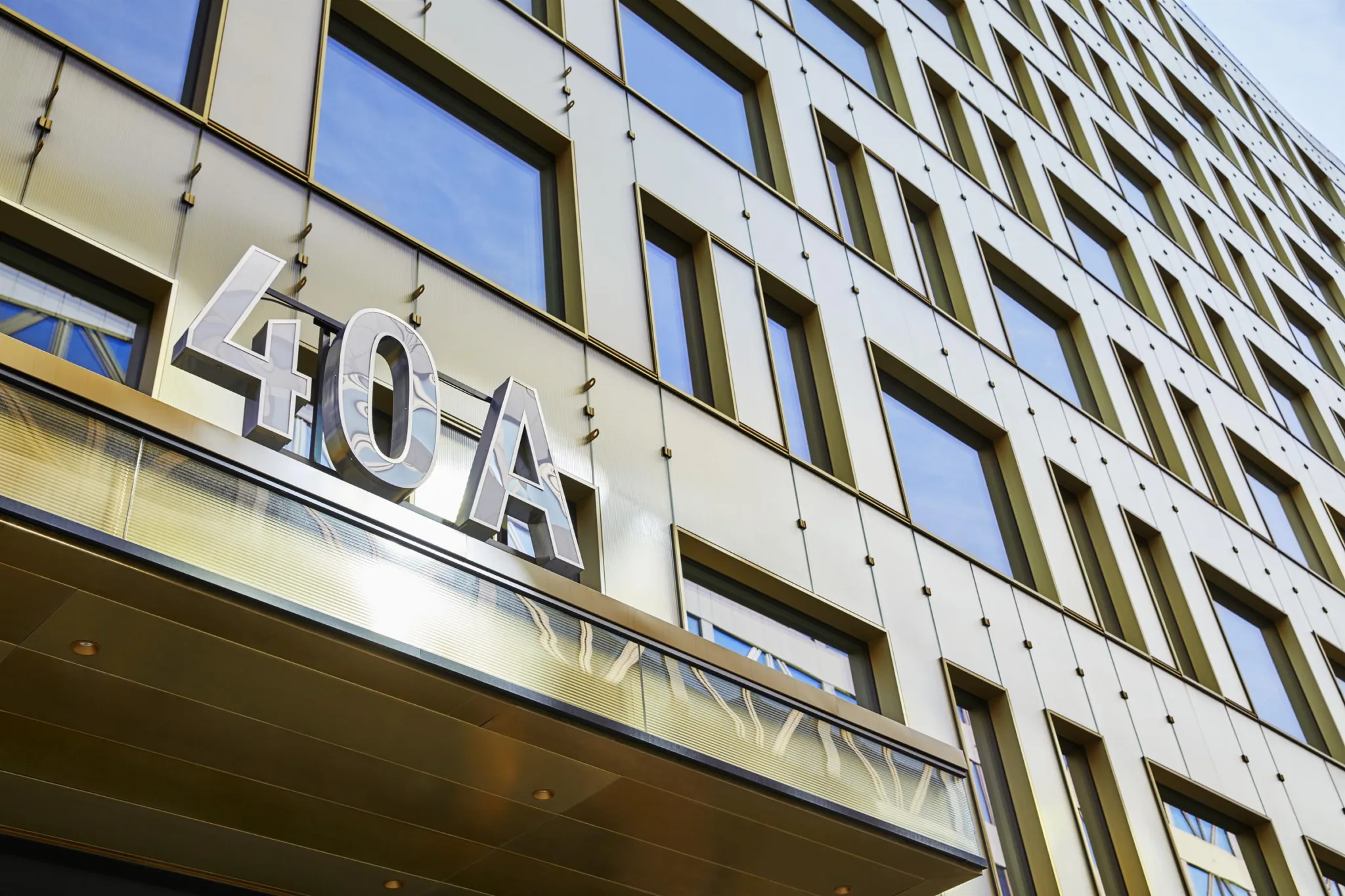 En byggnadsfasad med stora glasfönster och texten "40 A" synlig ovanför en entré.
