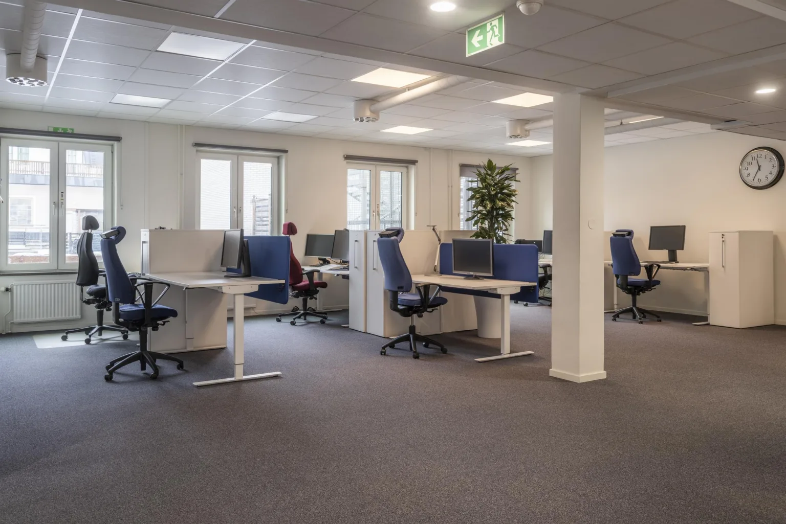5. Ett öppet kontorsutrymme med arbetsstationer, kontorsstolar och fönster.