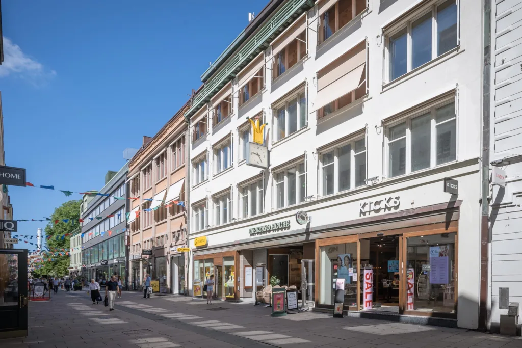 1. Gata med vita byggnader, skyltar och butiker under en klarblå himmel.