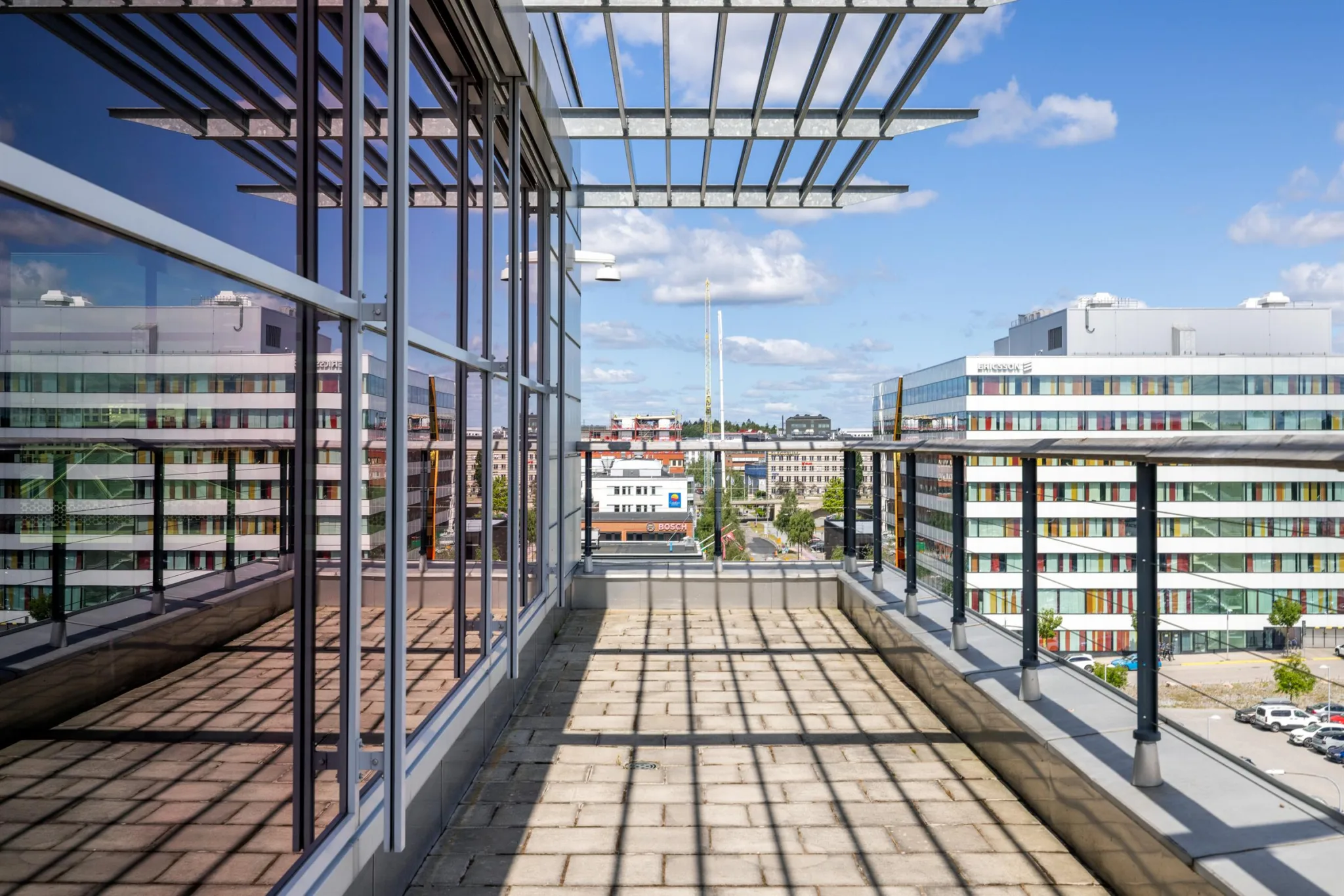 3. En takterrass med glasräcke och utsikt över stadens byggnader under en klar himmel.