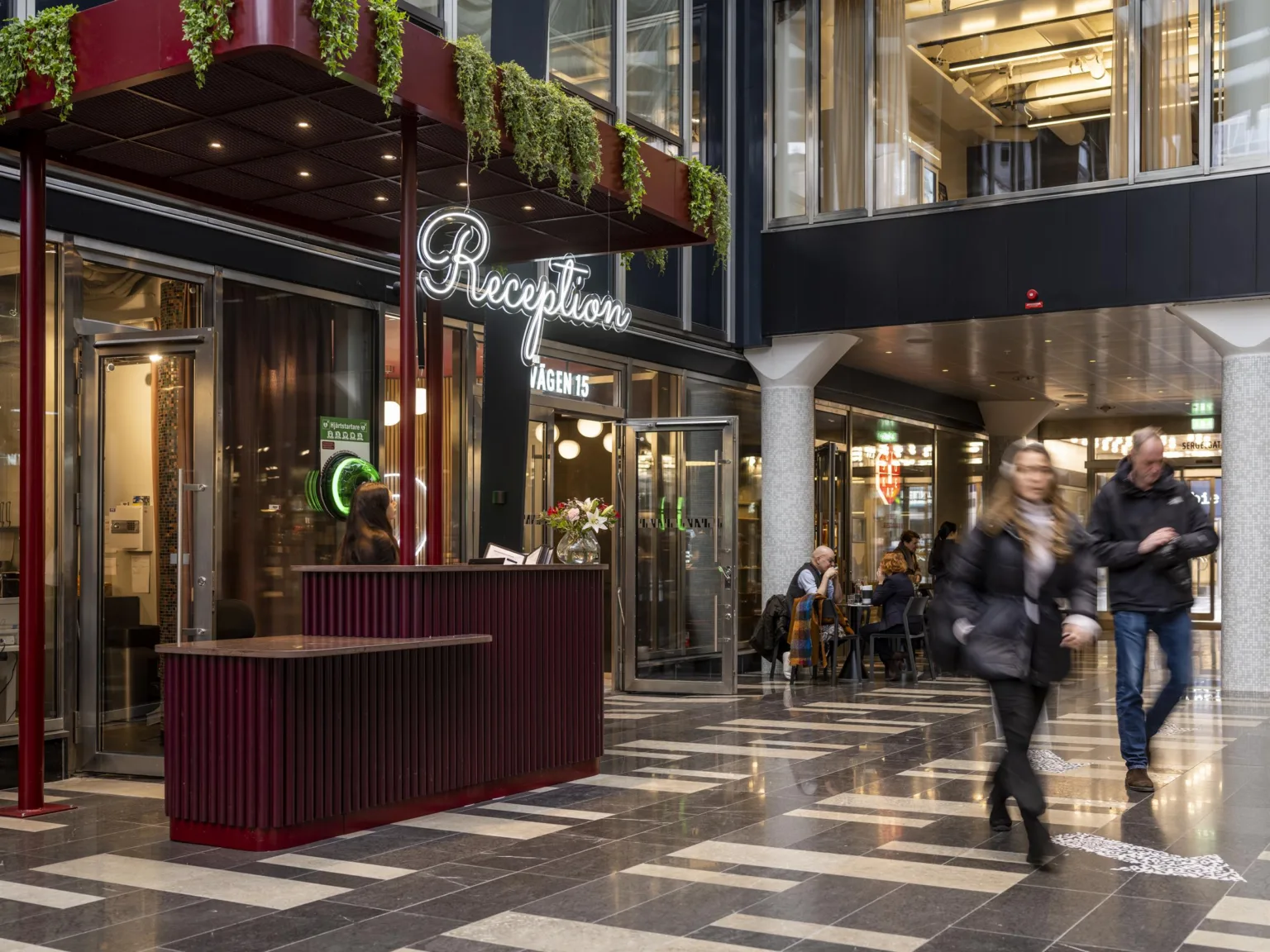 2. Reception i en modern byggnad med gröna växter på taket och glasfasad.