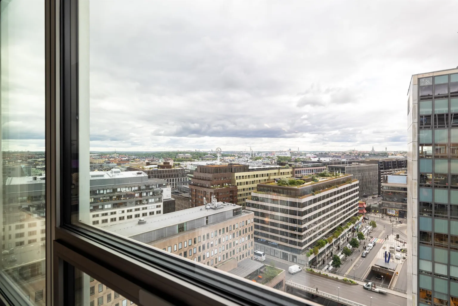 3. Utsikt över stadens byggnader genom ett fönster under en molnig himmel.