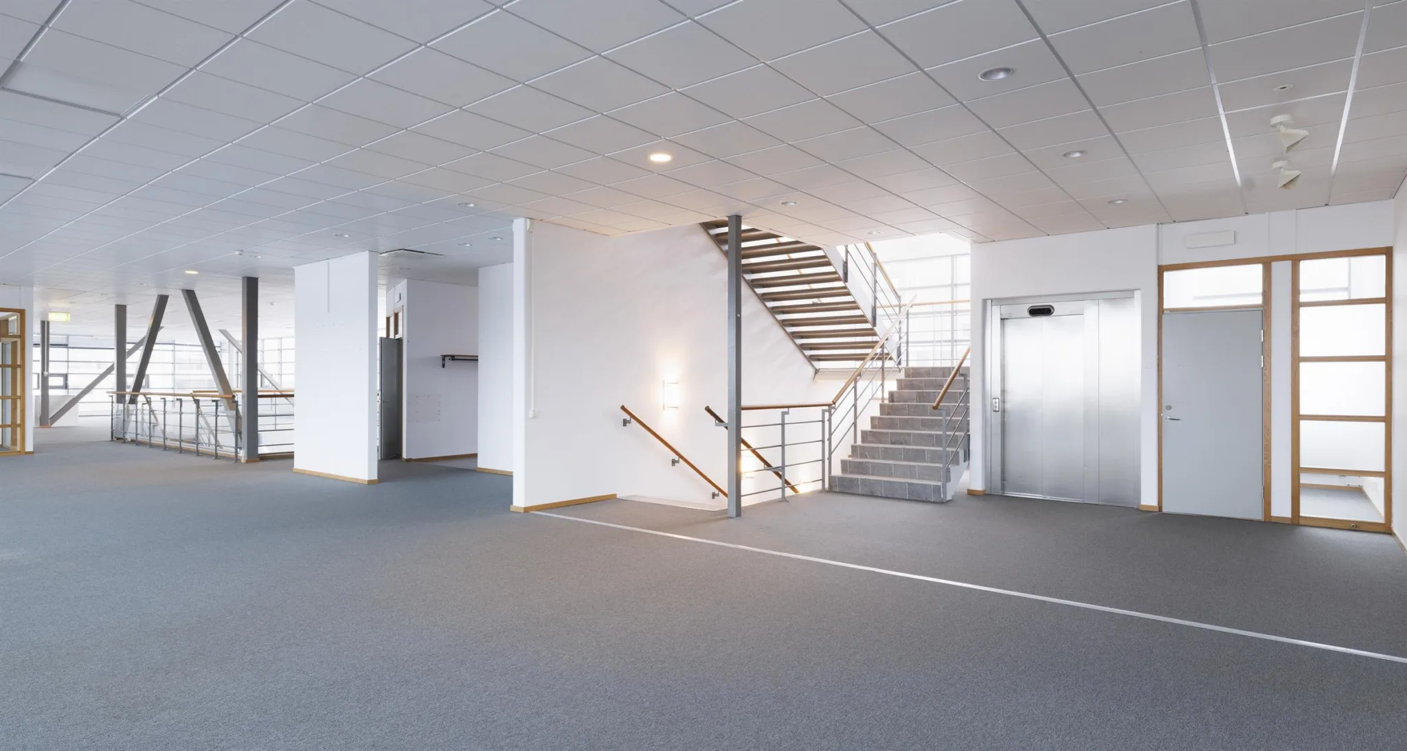 2. En modern kontorsmiljö med en trappa, hiss och vita väggar.