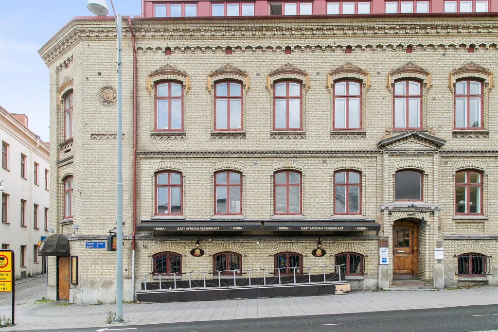 En närbild av samma gul tegelbyggnad, med fokus på dess fasad och uteservering.