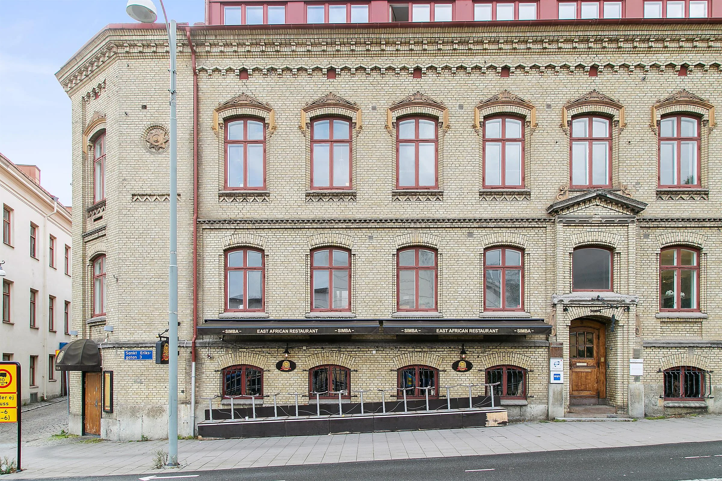 En närbild av samma gul tegelbyggnad, med fokus på dess fasad och uteservering.