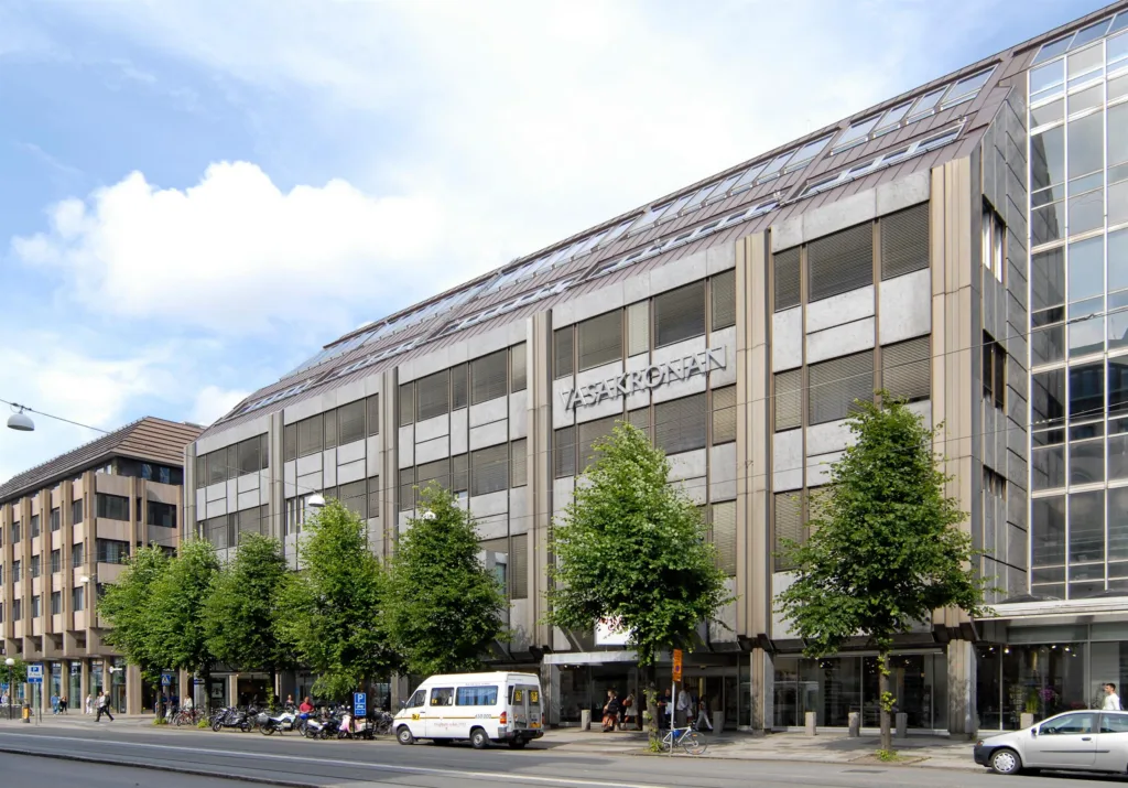 5. En byggnad med stora fönster och flera träd framför, med en vit skåpbil parkerad på gatan.