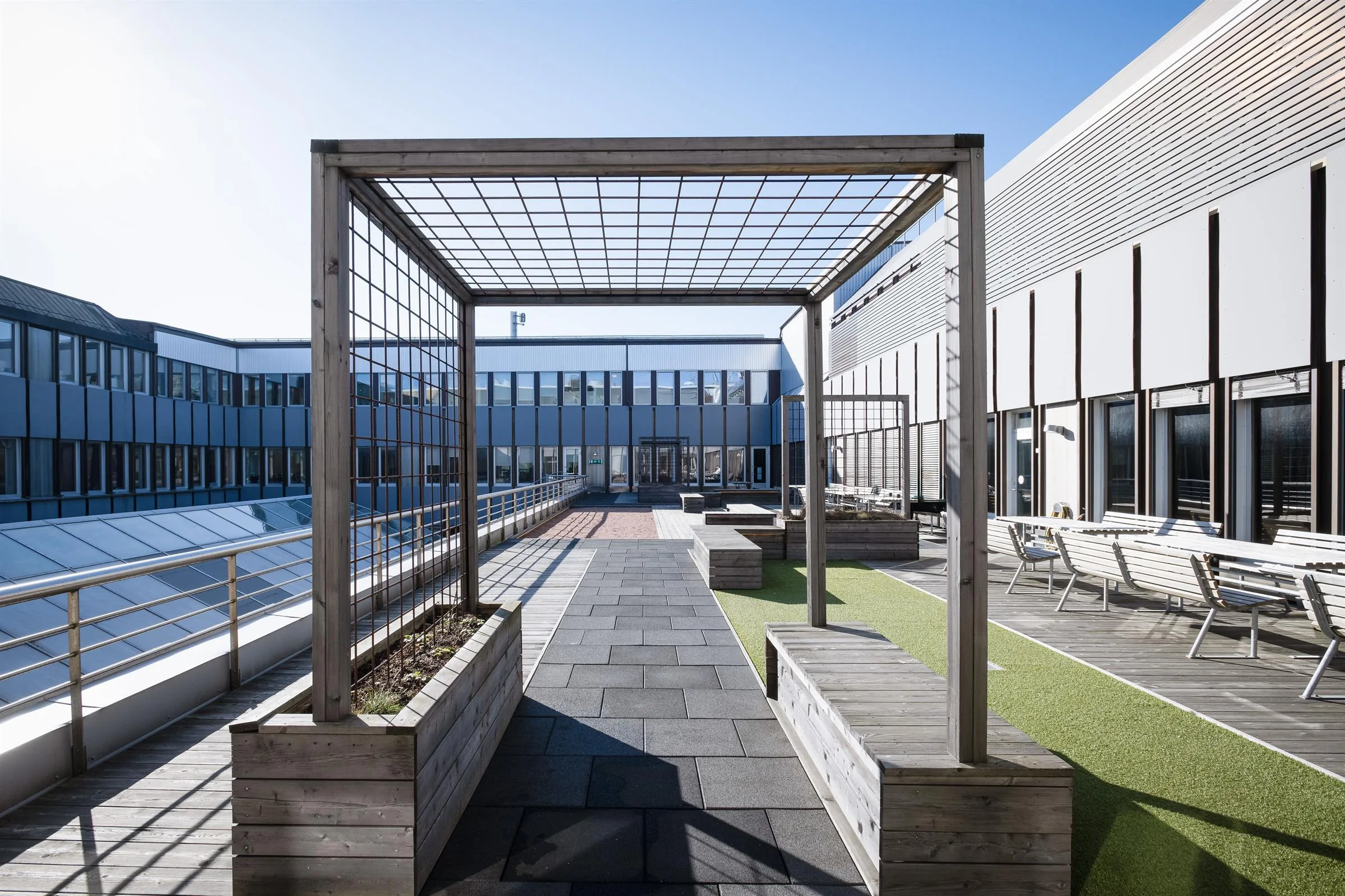 4. En takterrass med pergola, planteringslådor och sittplatser i en modern miljö.