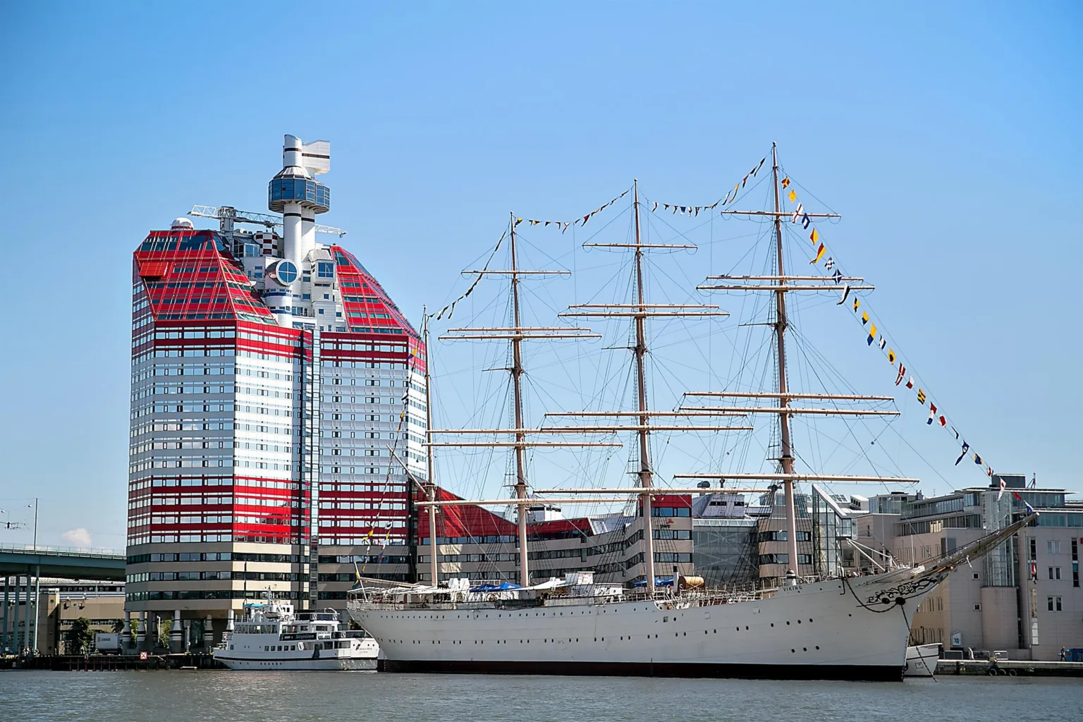 2. Ett högt rött och vitt byggnad med en stor segelbåt framför sig i en hamn.