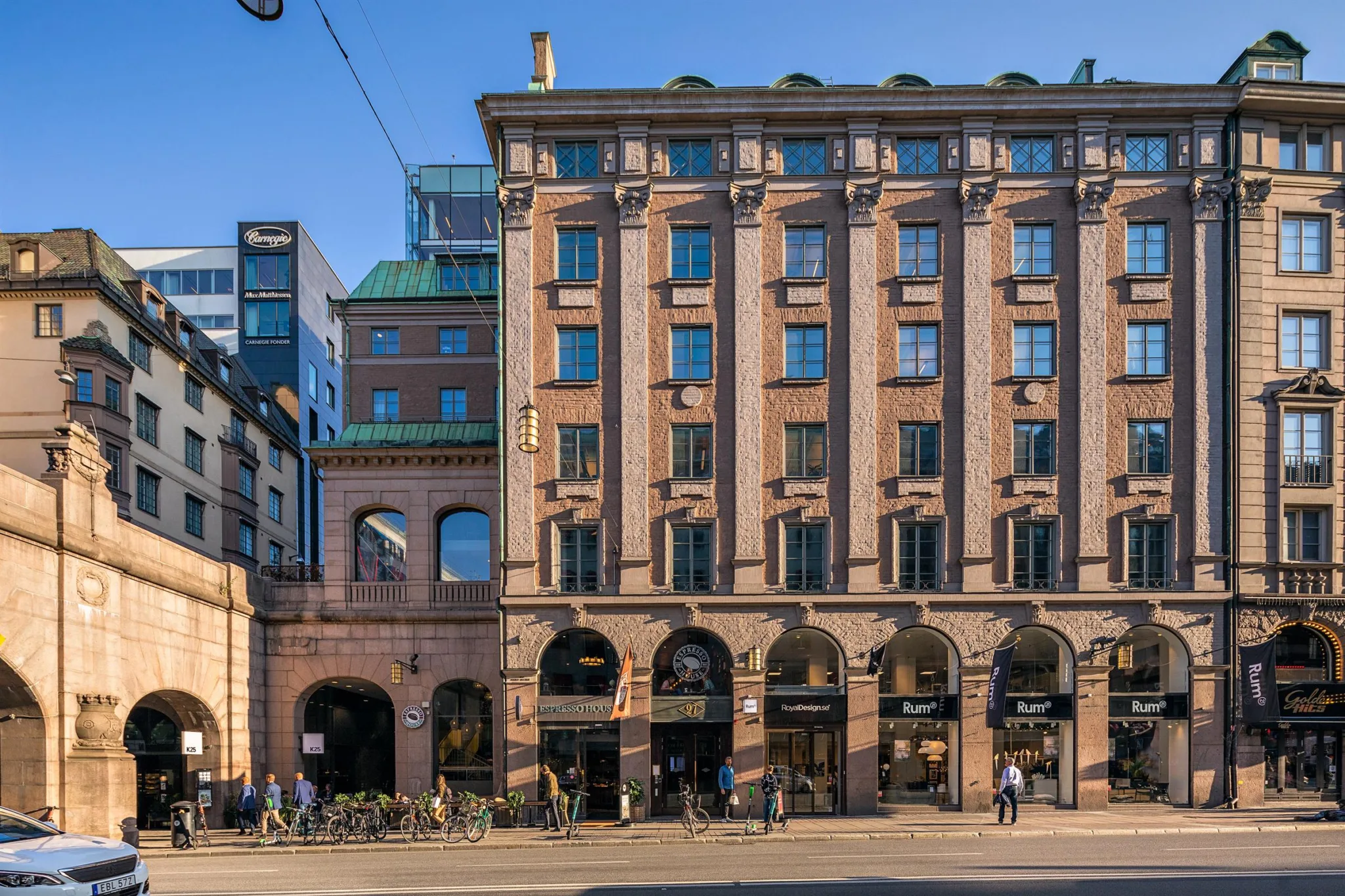 En klassisk byggnad med flera våningar, stora fönster och valvingångar, omgiven av stadsmiljö.