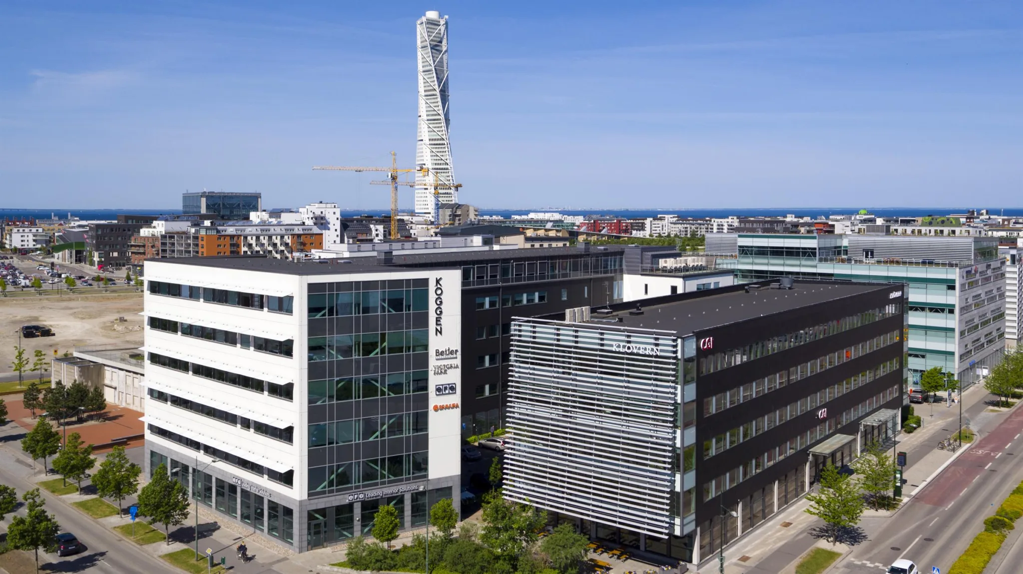 Exteriör av flera moderna byggnader, med Turning Torso synlig i bakgrunden.